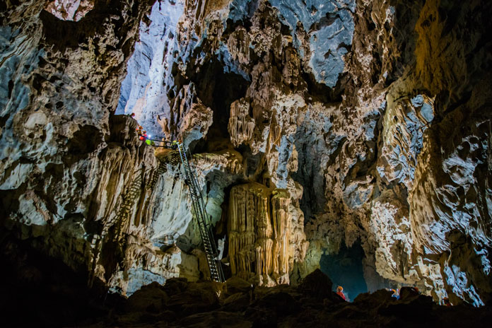 Descend a 10 m high ladder while wearing safety harnesses in Hang Ton Cave.